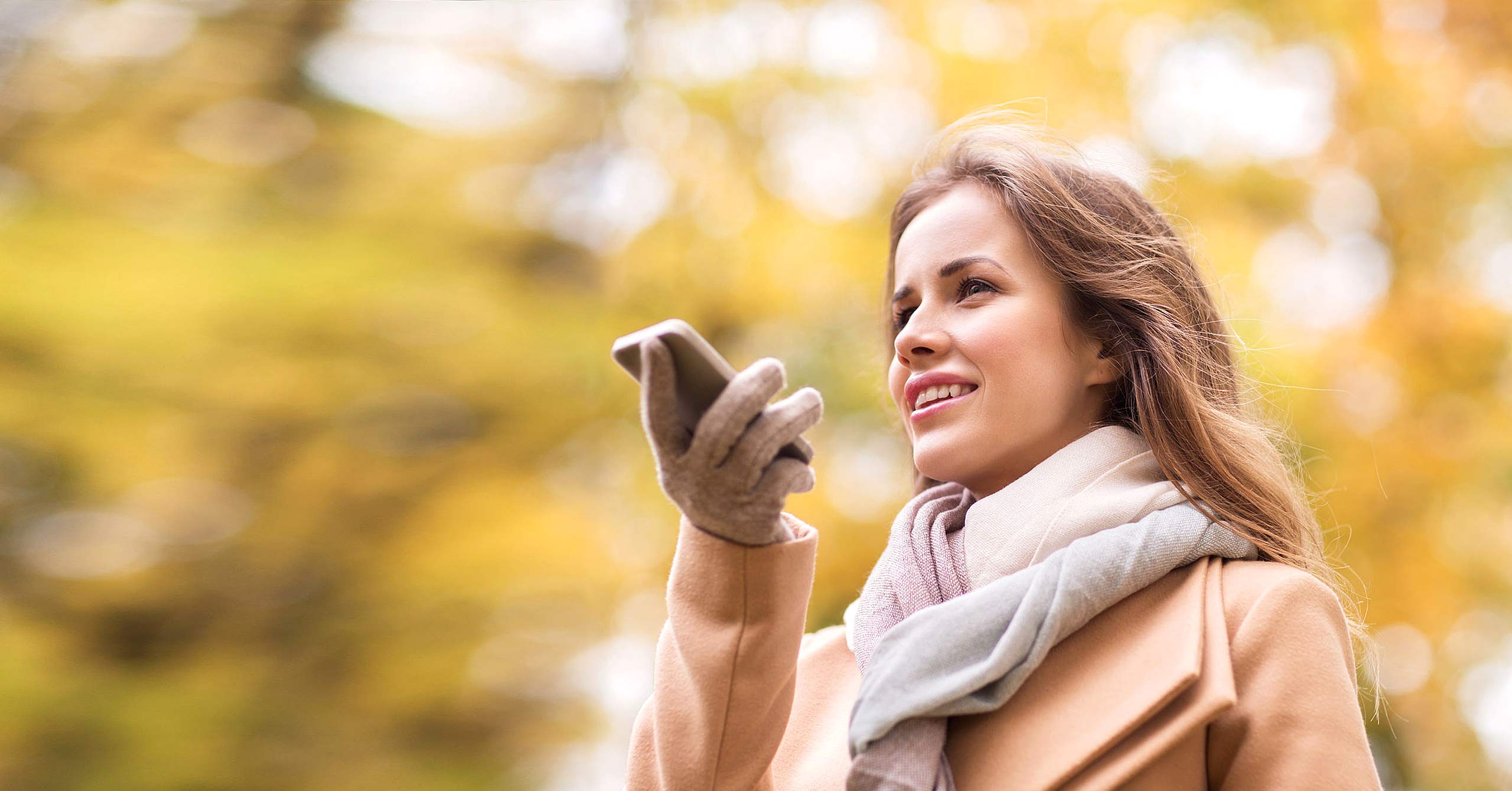 Woman recording voice on smartphone in autumn park
